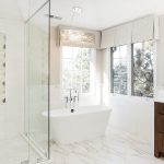 Modern bathroom with a freestanding tub and sleek custom window treatments for privacy and light control.