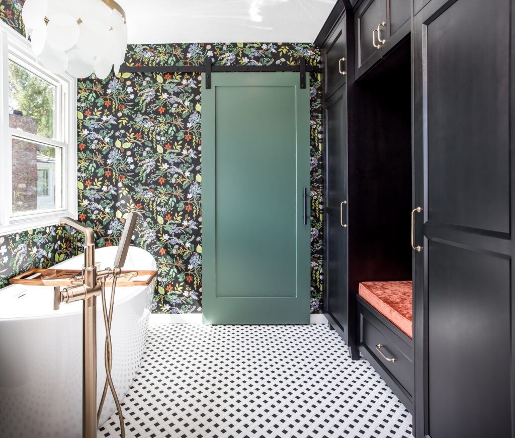 Modern primary bathroom remodel featuring a free-standing tub, custom cabinetry, and bold accent wall designed by Denver Design Group