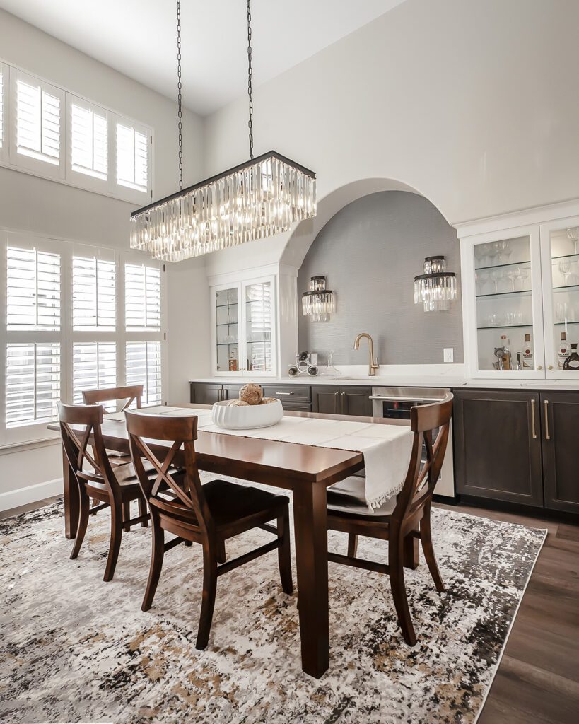 Modern elegance remodel dining room with York Shining Sisal black wallpaper, modern pendant lighting, and a chic dining table in an Englewood home remodel by Denver Design Group.