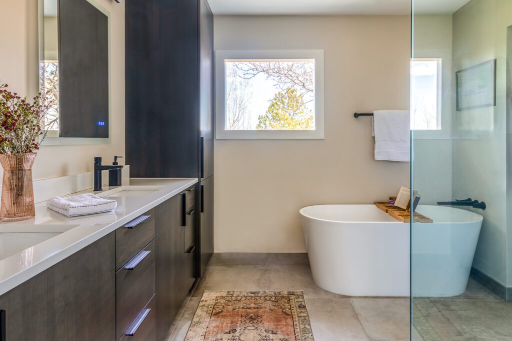 Sage green ceramic backsplash and freestanding tub in remodeled bathroom with modern spa-inspired design in Littleton home remodel by Denver Design Group