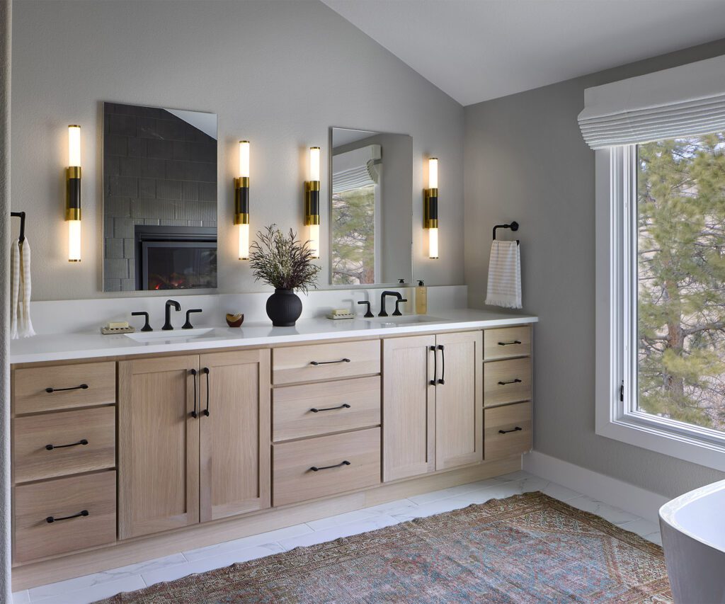 Lighted medicine cabinets with built-in outlets in modern primary bathroom design in Littleton remodel by Denver Design Group