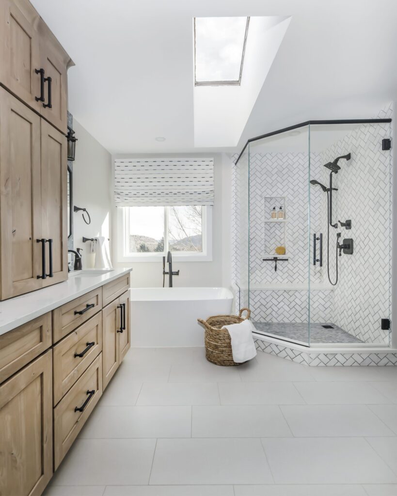 Freestanding bathtub and large glass-enclosed shower with heated floors and handmade tile by Denver Design Group.