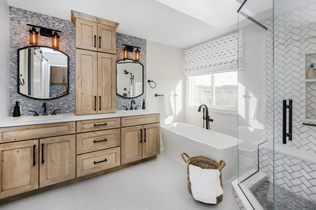 Modern farmhouse bathroom remodel in Littleton by Denver Design Group featuring freestanding tub, knotty alder double vanities, and neutral tile with blue accents.
