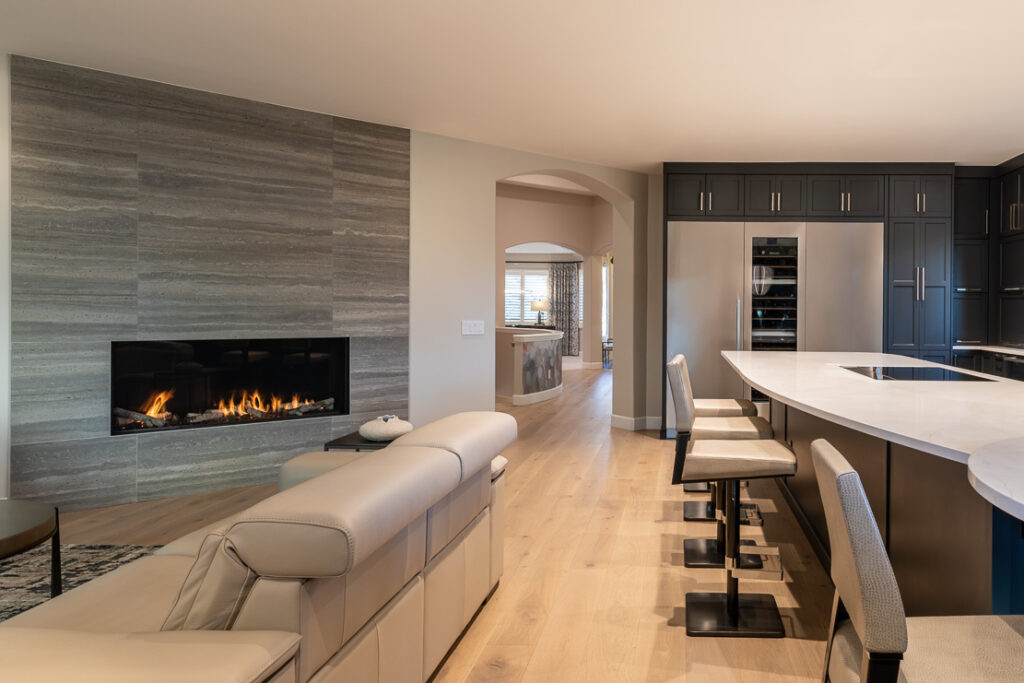 Linear gas fireplace with travertine marble tile wall finished in Decorative Material Orcia Greige Ant Stone in Greenwood Village living room