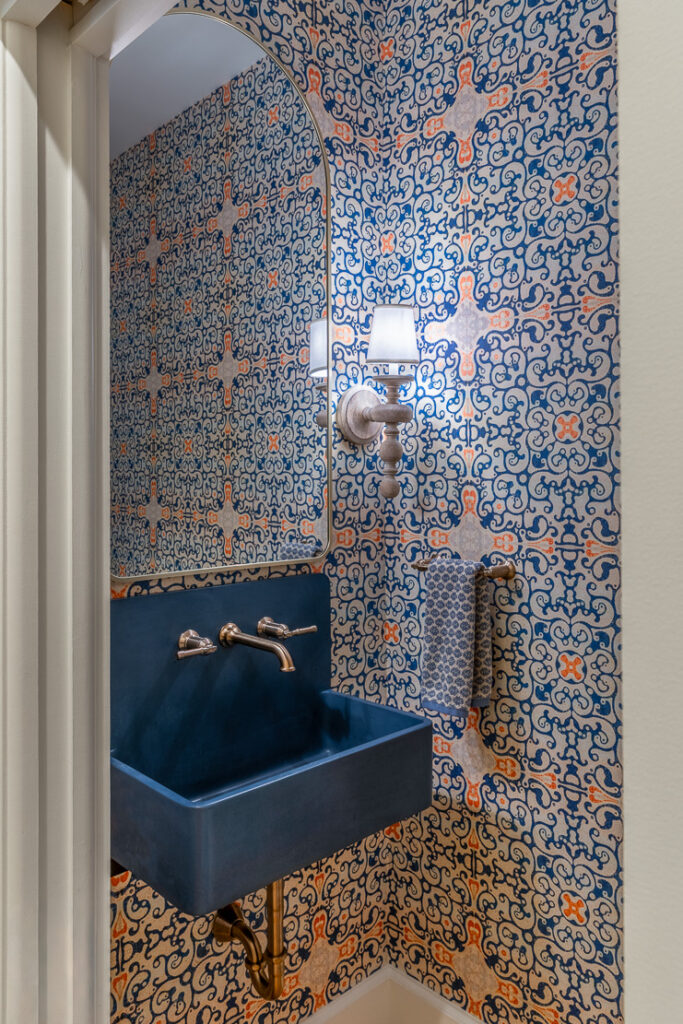Powder room with Spanish tile wallpaper and blue clay sink in Park Hill Denver Spanish Colonial remodel by Denver Design Group
