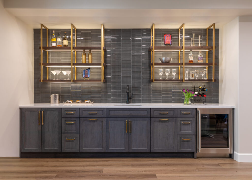 Basement bar with Vector Reverb charcoal tile and ceiling mounted walnut shelving with brass brackets Greenwood Village Colorado Denver Design Group