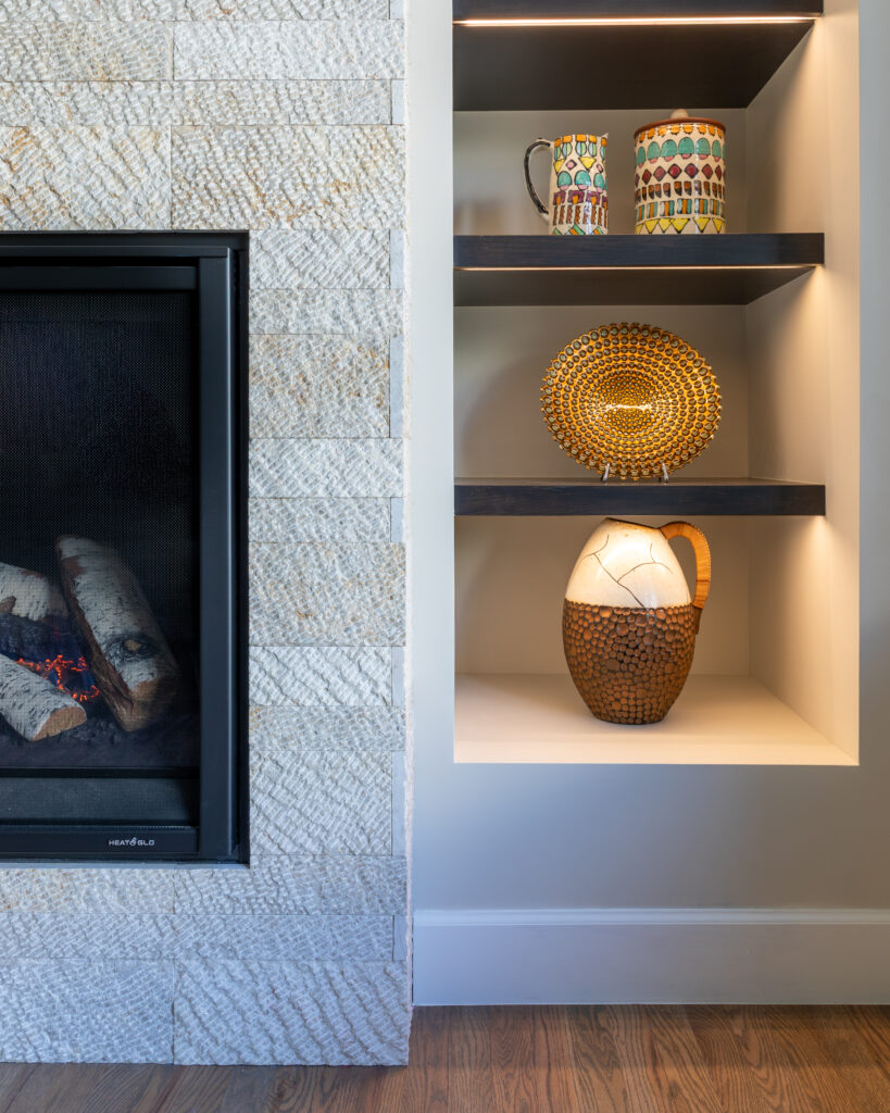 Family room fireplace detail with textured stone veneer and built-in shelving Greenwood Village Colorado Denver Design Group