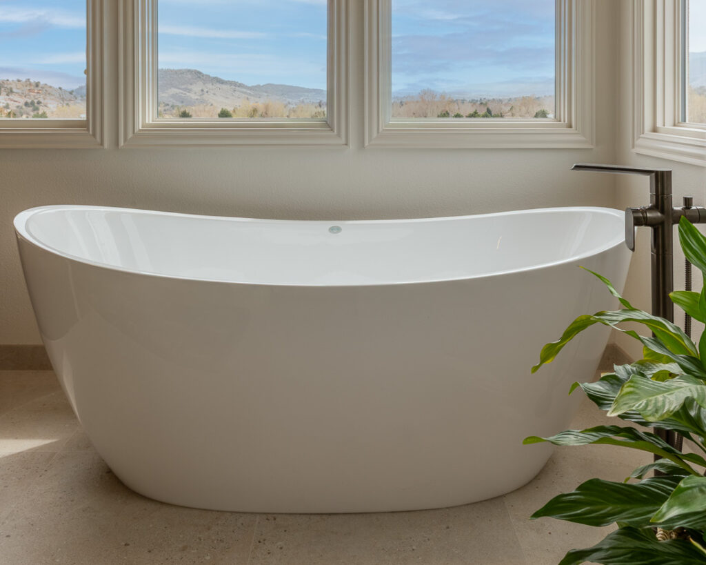 Freestanding soaking tub with floor-mounted brass faucet and large format tile primary suite Littleton Colorado Denver Design Group