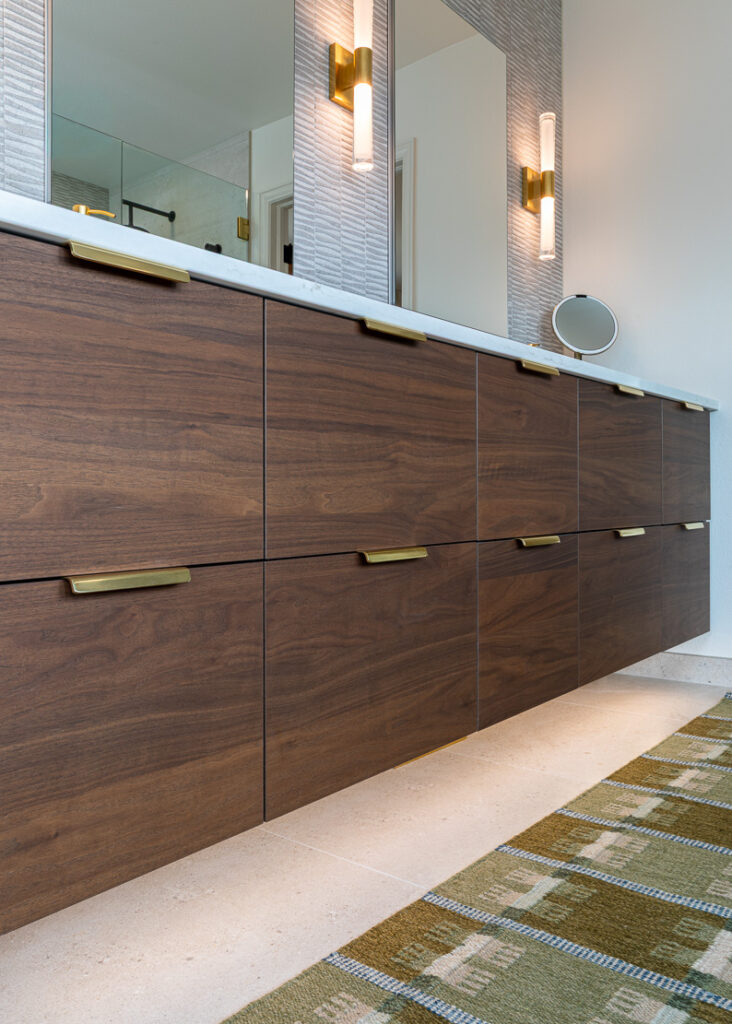Custom walnut floating vanity with integrated under-cabinet lighting primary bathroom remodel Littleton Colorado Denver Design Group